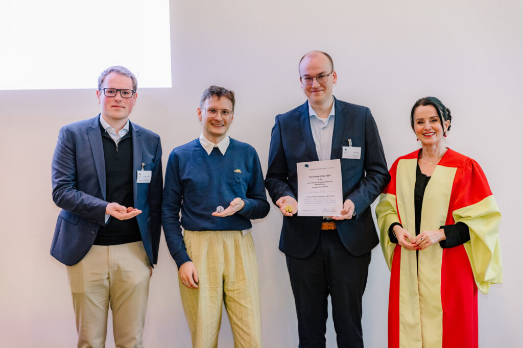 Four winners of the 2024 poster prize stand with their awards in front of a white wall. One holds a certificate, while the others present small brain models.