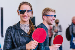 Man and a woman playing table tennis while wearing eye protection